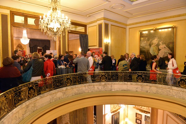 Delegates gathering on a gilded balcony during a congress break
