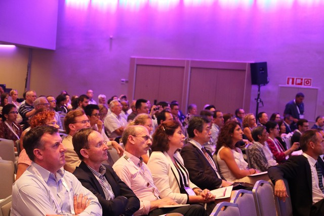 An audience following a session under purple stage light